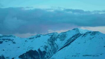 Zoom in background Time lapse shot of flying clouds over snowy Kazbegi caucasus mountain peaks during sunny day and clear blue sky video