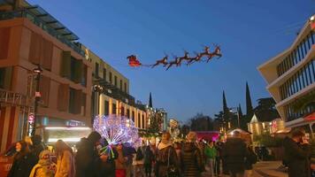 tbilisi, georgien, 2022, xmas installation santa på xmas transport med hjortar i himmel på jul marknadsföra med människor promenad i gator video