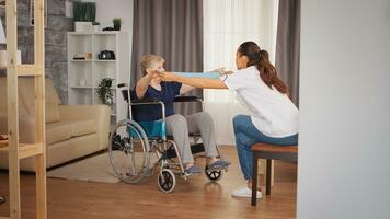 mayor mujer en silla de ruedas haciendo rehabilitación con resistencia banda. capacitación, deporte, recuperación y levantamiento, antiguo persona Jubilación hogar, cuidado de la salud enfermería, salud apoyo, social asistencia, médico y hogar Servicio foto