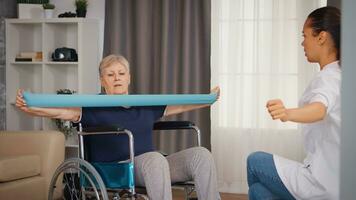 Senior woman in wheelchair doing rehabilitation treatment with assistance from nurse. Training, sport, recovery and lifting, old person retirement home, healthcare nursing, health support, social assistance, doctor and home service photo