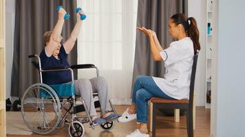 inválido mayor mujer en silla de ruedas formación con pesas durante rehabilitación con enfermero. capacitación, deporte, recuperación y levantamiento, antiguo persona Jubilación hogar, cuidado de la salud enfermería, salud apoyo, social asistencia, médico y hogar Servicio foto