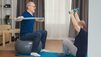 Energetic senior couple training in home using dumbbells and stability ball. Old person healthy lifestyle exercise at home, workout and training, sport activity at home photo
