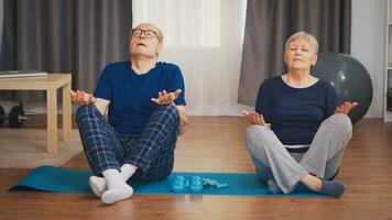 Senior couple doing breathing exercise on yoga mat in living room. Old person healthy lifestyle exercise at home, workout and training, sport activity at home photo