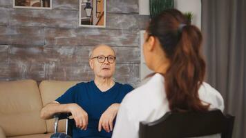 Senior patient in wheelchair talking with medical worker. Disabled disability old person with medical worker in nursing care home assistance, healthcare and medicine service photo