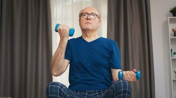 mayor hombre formación bíceps en vivo habitación. antiguo persona pensionista sano formación cuidado de la salud deporte a hogar, hacer ejercicio aptitud actividad a mayor años foto