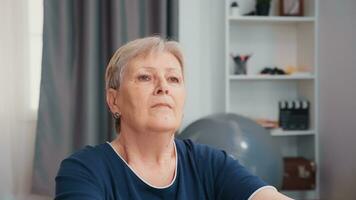 Senior woman doing breathing exercise while meditating in living room. Old person pensioner exercise training at home sport activity at elderly retirement age photo