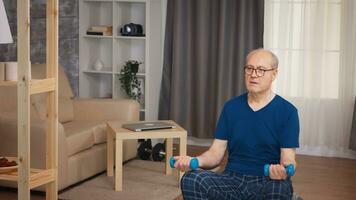 Pensioner doing biceps training on balance ball in living room. Old person pensioner healthy training healthcare sport at home, exercising fitness activity at elderly age photo