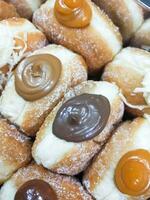 Doughnuts with chocolate and coconut on display at a market stall. photo