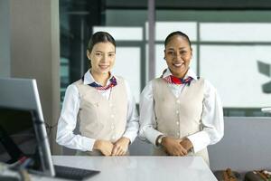 Team of diversity flight attendant posing with smile at the check in counter before boarding aircraft to welcome passenger on board for airline service and airplane transportation concept photo