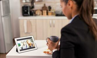 mujer en negocio traje hablando en línea con amigos en un digital tableta foto