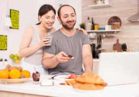 Couple talking online with family on a video call during breakfast. Videoconference in the morning, using online web internet technology, talking and communicating with relatives photo