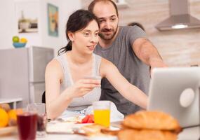 Couple doing online shopping on laptop during breakfast. Entering information, customer using ecommerce technology buying stuff on the web, cosumerism banking and ordering photo