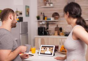 Couple talking online with family on a video call during breakfast. Videoconference in the morning, using online web internet technology, talking and communicating with relatives photo
