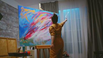 Young artist looking at her colorful abstract painting. photo