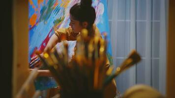 Young artist using fingers while painting on large canvas in art studio. photo