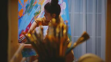 Young artist using fingers while painting on large canvas in art studio. photo