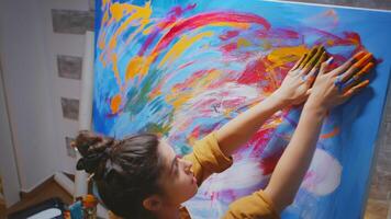 Woman using hand fingers while painting on large canvas in art studio. photo