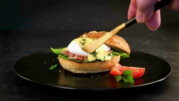 Breakfast. Sandwich with ham, poached egg, onion and arugula in a plate on a dark background video