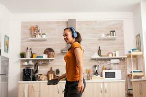 Woman full of happiness dancing in the kitchen at breakfast. Energetic, positive, happy, funny and cute housewife dancing alone in the house. Entertainment and leiuse alone at home photo