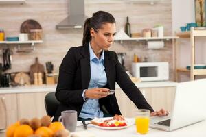 Woman using credit card in the morning before going to work. Shopping online for goods and clothes, using modern technology in every day life, making payments via internet. photo