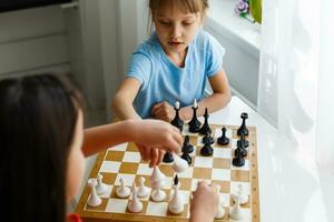 dos lindos niños jugando al ajedrez en casa foto
