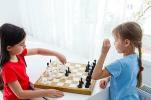 Two little sister playing chess at home photo