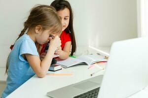 Pretty stylish schoolgirls studying during her online lesson at home, social distance during quarantine, self-isolation, online education concept photo