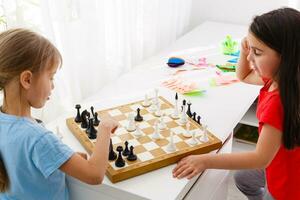 Two cute children playing chess at home photo