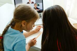 Pretty stylish schoolgirls studying during her online lesson at home, social distance during quarantine, self-isolation, online education concept photo