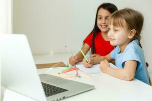 Pretty stylish schoolgirls studying math during her online lesson at home, social distance during quarantine, self-isolation, online education concept photo