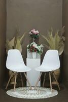 Background for photos in the photo studio with a brown theme and aesthetic white chairs decorated with artificial flowers