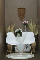 Background for photos in the photo studio with a brown theme and aesthetic white chairs decorated with artificial flowers