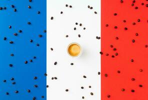 Creative layout made of cup of coffee and coffee beans on flag of France as a background. Minimal coffee concept. Trendy espresso idea. Unique flat lay composition. Coffee aesthetic. photo