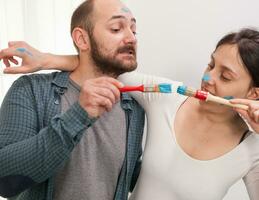 Couple playing with paint brushes during home renovation. Apartment redecoration and home construction while renovating and improving. Repair and decorating. photo