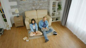 Top view of young couple browsing on laptop and smartphone sitting on carpet. photo