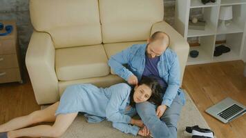 Young man playing with wife's hair while relaxing on carpet. photo