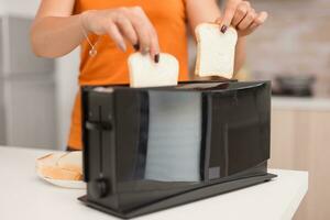 Roasting bread popping out of toaster in kitchen for breakfast. Bread preparation for delicous breakfast. Healthy morning in cozy interior, delicious home meal preparation photo