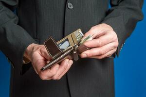 A man in a suit holds a wallet. Men's hands take out or put a bill in a wallet. photo