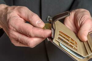 A man in a suit holds a bitcoin and a wallet in his hand. photo