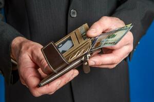 A man in a suit holds a wallet. Men's hands take out or put a bill in a wallet. photo