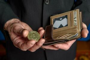 A man in a suit holds a bitcoin and a wallet in his hand. photo