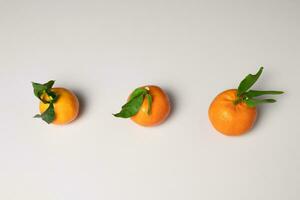 three tangerines with leaves on a white background. View from above. Photo. photo