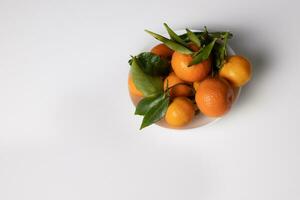 Tangerines with green twigs on a white table. Photo. Space for text. photo