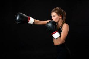 Beautiful female athlete in boxing gloves, in the studio on a black background. photo