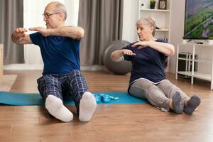 Senior couple enjoying physical training at home. Old person healthy lifestyle exercise at home, workout and training, sport activity at home on yoga mat. photo