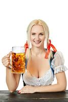 Young bavarian woman in dirndl sitting at table with beer on white background photo