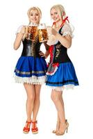 Full length portrait of a two blond womans with traditional costume holding beer glasses isolated on white background. photo