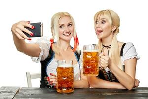 dos hermosa mujer participación un vaso de cerveza mientras sentado a un de madera mesa en un blanco antecedentes en el estudio foto