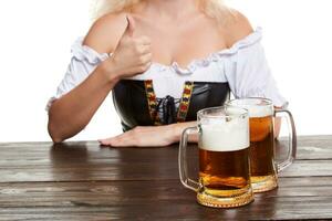 Beautiful young blond girl in traditional costume drinks out of oktoberfest beer stein. photo