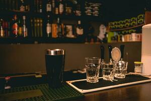 Empty glasses and cocktail shaker standing on bar counter photo